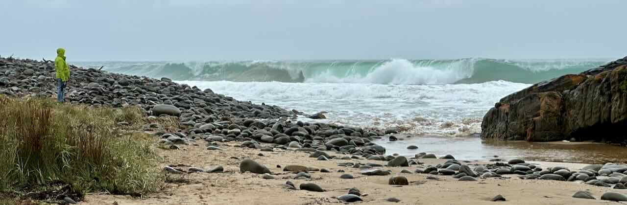 Rocky beach with waves and a person in a yellow jacket